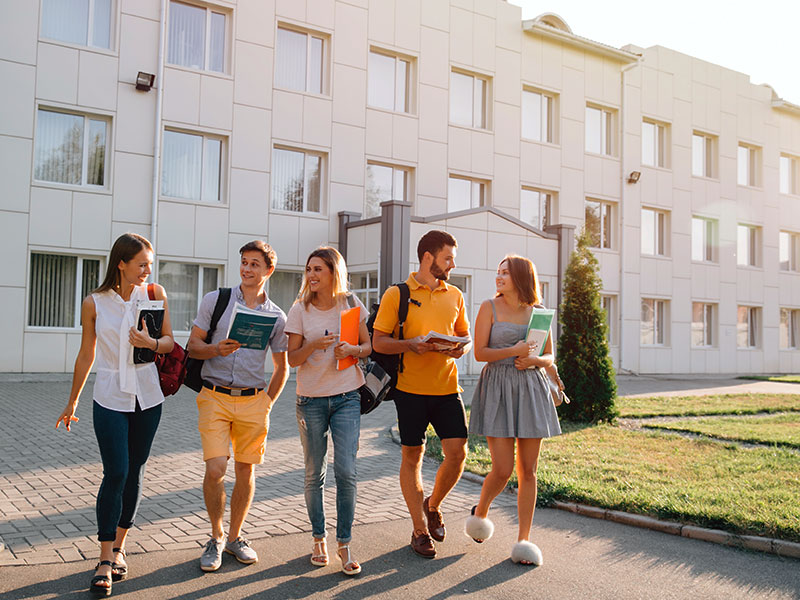 College students walking on campus heading to class. Student house properties have potential risks, so landlords should consider protecting their investments with a comprehensive student housing insurance policy.