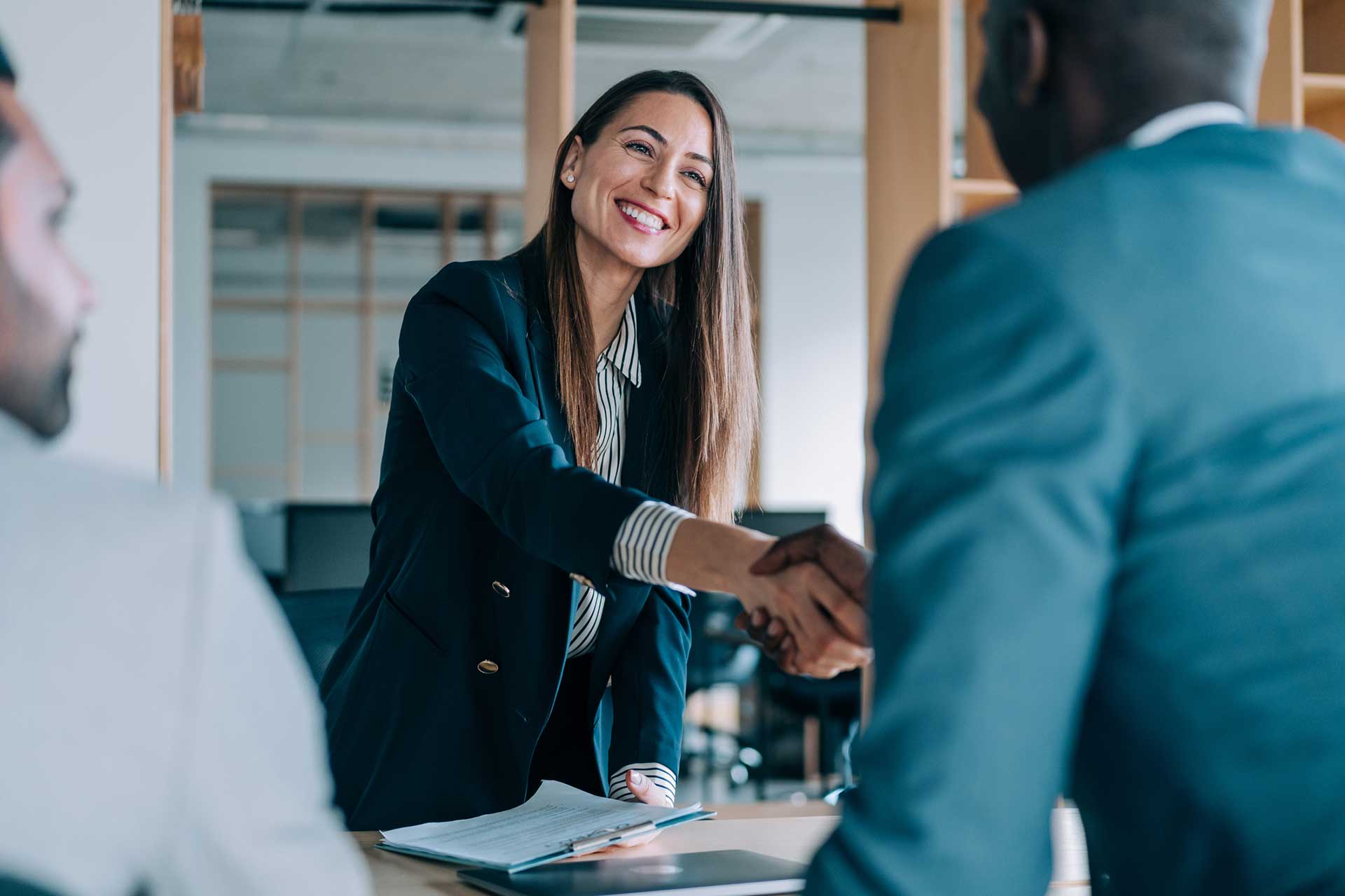 A friendly female insurance agent greeting male African-American clients.